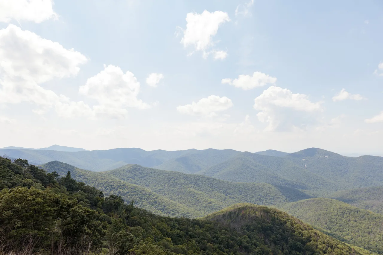 Layers of tree-covered Blue Ridge mountains fading into a hazy sky from Rockytop Overlook